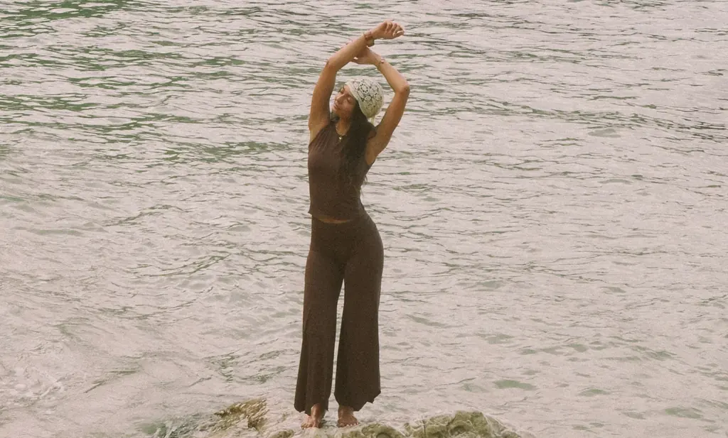 A woman stretching on a rock in rippling water